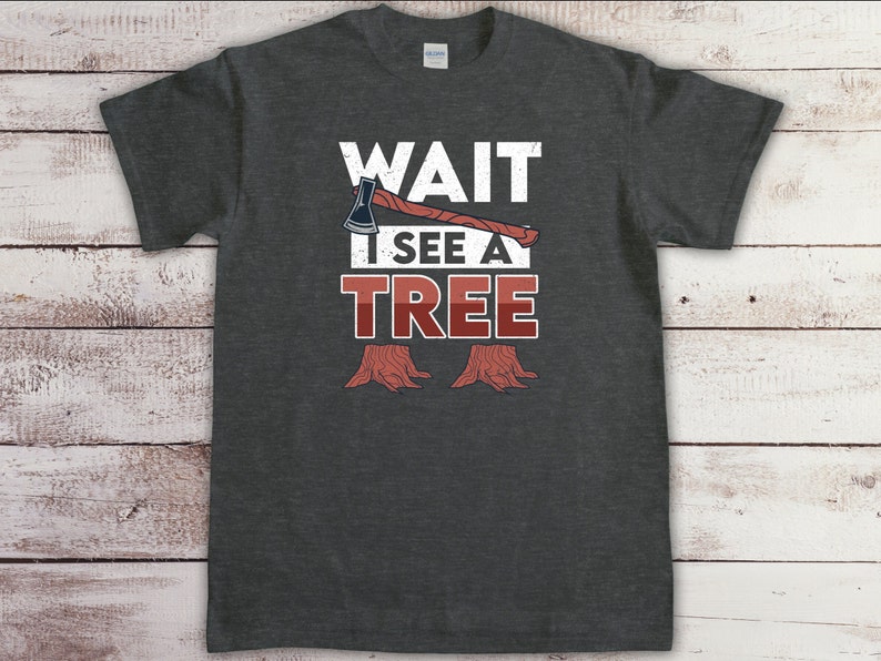 May include: A dark gray t-shirt with a white graphic that says "WAIT I SEE A TREE" with an axe and tree stumps.