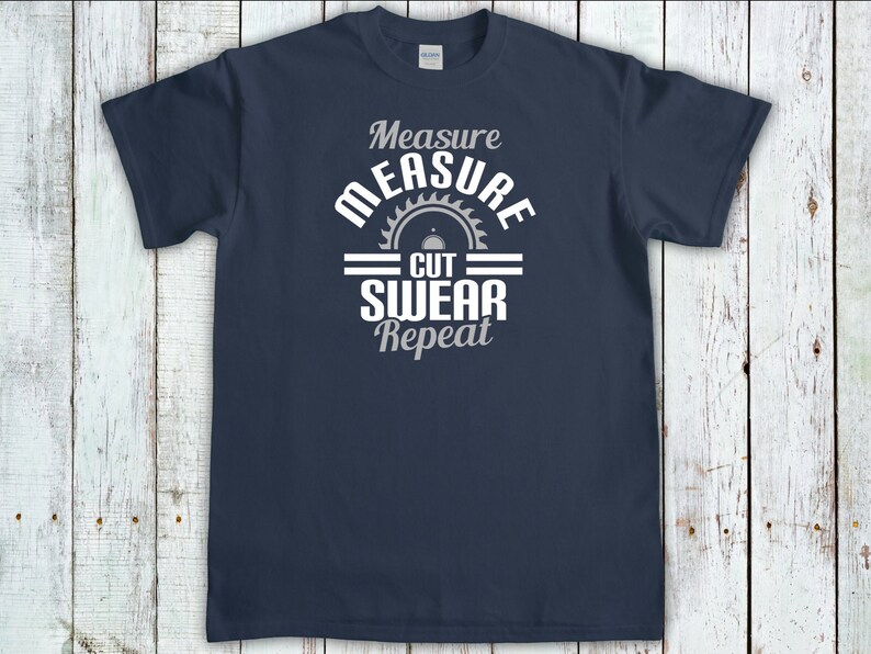 May include: A navy blue t-shirt with a white graphic that says "Measure Measure Cut Swear Repeat" with a saw blade icon.