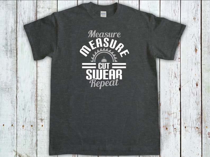 May include: Dark gray t-shirt with a white graphic design that says "Measure Measure Cut Swear Repeat" with a saw blade graphic.