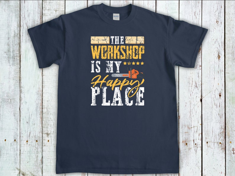 Peut inclure: Un t-shirt bleu marine avec un design graphique vieilli qui dit "The Workshop is my Happy Place" avec un graphique de tron&ccedil;onneuse.
