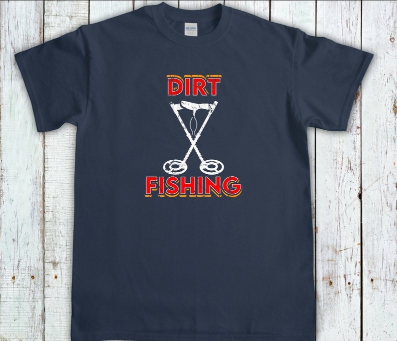 May include: A navy blue t-shirt with the text "DIRT FISHING" in red and yellow with a white silhouette of two metal detectors crossed over each other.