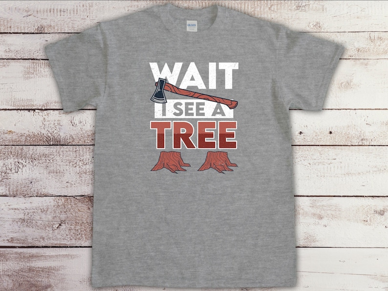 May include: A gray t-shirt with the text "WAIT I SEE A TREE" in white with a red and brown axe and two tree stumps.