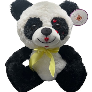 May include: A plush black and white panda bear with a yellow bow. The panda has red hearts on its face and a red heart-shaped nose.