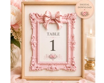 May include: A light wood frame containing a table number sign with the text TABLE 1. The sign features a pink ornate border with a sculpted bow at the top and a floral graphic at the bottom. A circular badge in the corner reads DIGITAL DOWNLOAD.