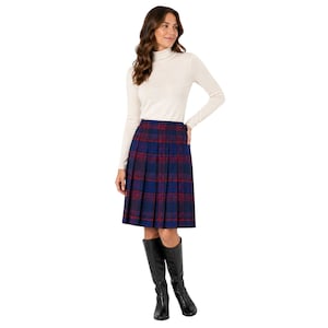 May include: A long-sleeved cream-colored turtleneck sweater paired with a knee-length pleated skirt featuring a blue and red plaid pattern. The outfit is completed with black knee-high boots, creating a coordinated ensemble for cooler weather.