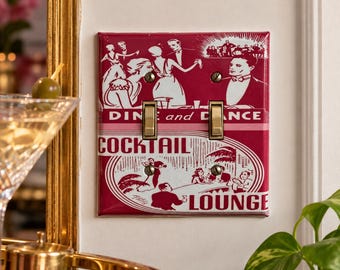 May include: A rectangular double light switch plate featuring a deep red and white graphic print. The design displays figures in formal attire with the text DINE and DANCE and COCKTAIL LOUNGE. It includes two metallic toggle switches and four screws.
