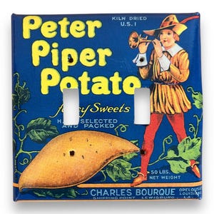 Pode incluir: Uma placa de interruptor de luz vintage com um fundo azul e uma ilustração amarela e laranja de uma batata doce, uma videira e um homem com um traje amarelo e vermelho tocando trombeta. O texto "Peter Piper Potato" está impresso em letras amarelas. O texto "for Fancy Sweets" está impresso em letras pretas. O texto "Kiln Dried U.S.I" está impresso em letras pretas. O texto "50 lbs. Net Weight" está impresso em letras pretas. O texto "Charles Bourque, Shipping Point Lewisburg, LA, Opelousas, Louisiana" está impresso em letras pretas.