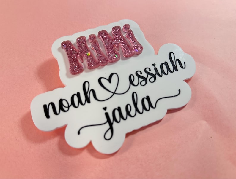 May include: White vinyl sticker with pink glitter lettering that says "Mimi" and black lettering that says "noah &hearts; essiah jaela"