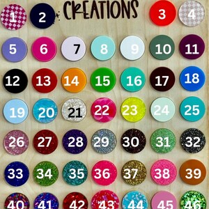 May include: A wooden board with 53 numbered, round, colorful, decorative phone grips. The board has the text "Paislee Lane Creations" at the top.
