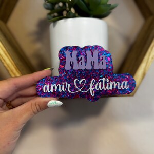 May include: A pink and blue glitter sign with the text "Mama" in purple and "amir &hearts; fatima" in white.