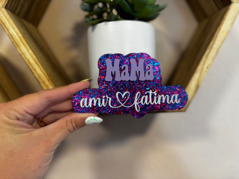 May include: A pink and blue glitter sign with the text "Mama" in purple and "amir &hearts; fatima" in white.