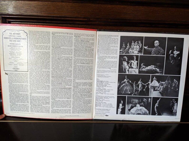 May include: A black and white vinyl record album cover featuring a photo of Yul Brynner in a black and white polka dot shirt. The album is for the musical "The King and I" by Rodgers and Hammerstein. The album cover also includes photos of the cast performing in the musical.