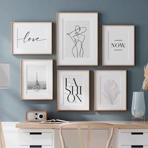 Peut inclure: Un bureau &agrave; domicile avec un mur bleu clair, un bureau blanc &agrave; quatre tiroirs, une chaise en bois, une lampe, un vase avec de l'herbe de pampa s&eacute;ch&eacute;e et six impressions encadr&eacute;es au mur. Les impressions pr&eacute;sentent les mots "love", "fashion", "now", et un dessin au trait d'une femme, une photo de la tour Eiffel et une plume.