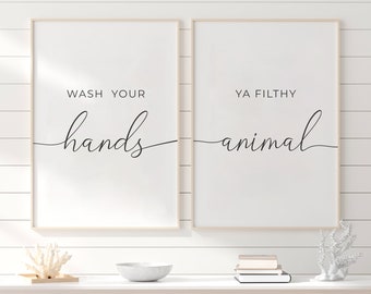 May include: Two framed prints with black calligraphy on a white background. The left print says "Wash your hands". The right print says "Ya Filthy Animal".