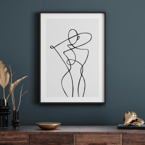 Peut inclure: Un dessin au trait noir et blanc d'un corps humain dans un style minimaliste, encadr&eacute; dans un cadre noir sur un mur bleu fonc&eacute;.