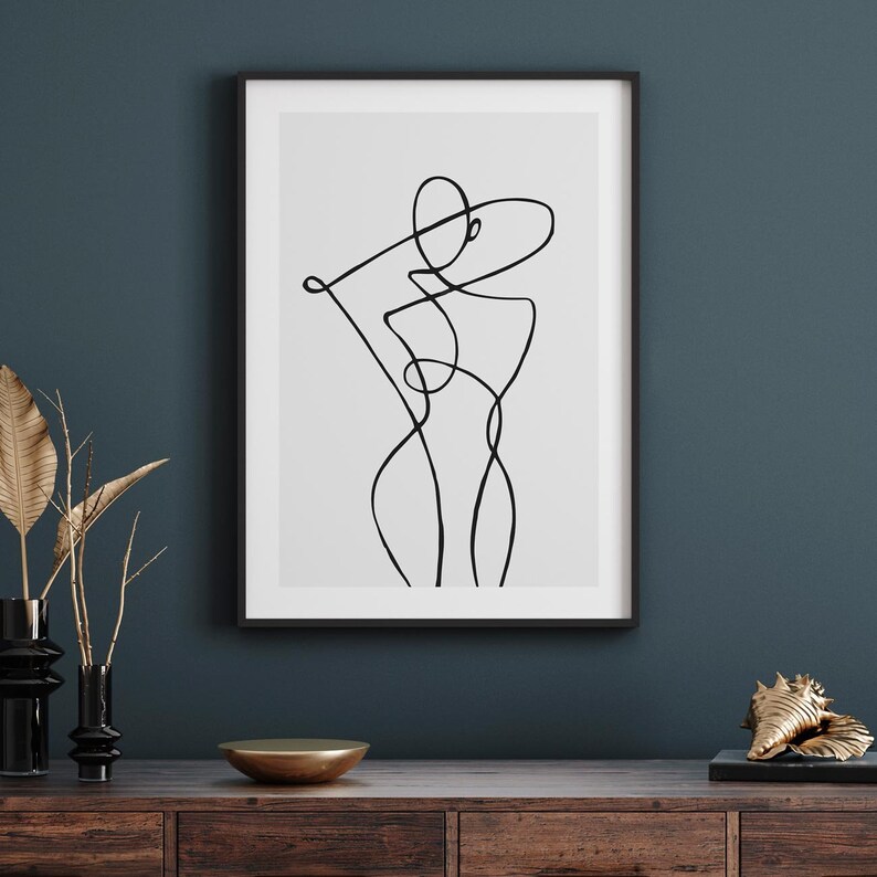 Peut inclure: Un dessin au trait noir et blanc d'un corps humain dans un style minimaliste, encadr&eacute; dans un cadre noir sur un mur bleu fonc&eacute;.