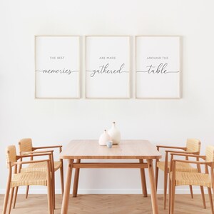 May include: A dining room setting with a wooden table and chairs. Three framed prints on the wall display the text "The best memories are made gathered around the table." Vases are on the table.