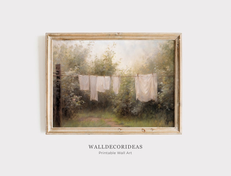 May include: A framed painting of a clothesline with white laundry hanging in a lush green forest setting. The painting has a vintage feel and is framed in a light wood frame.