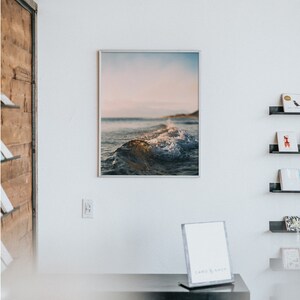 May include: A framed photograph of a wave breaking on a beach with a blue and pink sky in the background.