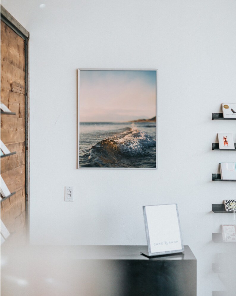 May include: A framed photograph of a wave breaking on a beach with a blue and pink sky in the background.
