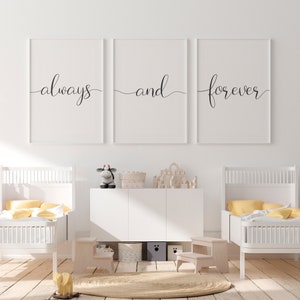 May include: Three white framed prints with black calligraphy that reads "always", "and", and "forever". The prints are hanging on a white wall above a white dresser with two white cribs on either side.