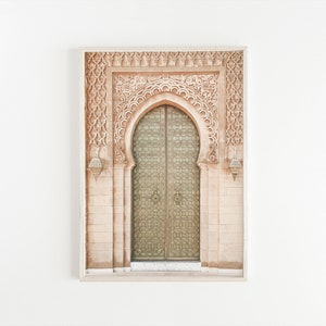 May include: A framed photograph of a decorative archway with intricate carvings and a large, ornate wooden door with metal accents. The door is closed and the archway is made of a light brown stone.