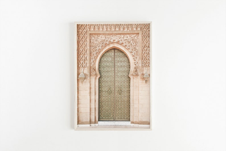 May include: A framed photograph of a decorative archway with intricate carvings and a large, ornate wooden door with metal accents. The door is closed and the archway is made of a light brown stone.