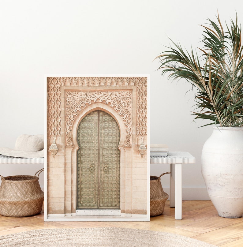 May include: A framed print of a decorative archway with a large, ornate door. The door is made of metal and has a geometric pattern. The archway is made of stone and has intricate carvings.