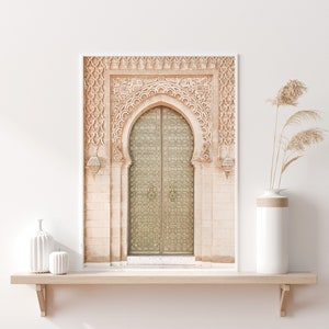 May include: A photograph of a large, ornate, arched doorway with intricate carvings and a double wooden door with a geometric pattern. The door is a light green color and the surrounding architecture is a light beige color.