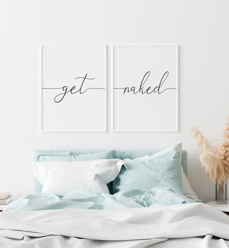 Puede incluir: Dos impresiones enmarcadas blancas con caligraf&iacute;a negra sobre fondo blanco. Las impresiones est&aacute;n colgadas sobre una cama con un edred&oacute;n y almohadas de color azul claro. El texto en las impresiones dice "get" y "naked".