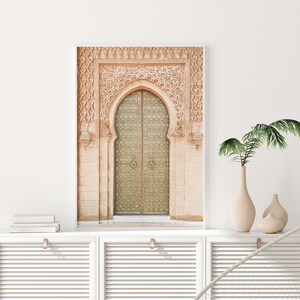 May include: A photograph of a large, ornate, arched doorway with a double wooden door. The door is made of wood and has intricate carvings. The door is painted a light green color. The doorway is made of stone and has a light brown color. The doorway is surrounded by a white frame.