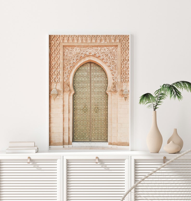 May include: A photograph of a large, ornate, arched doorway with a double wooden door. The door is made of wood and has intricate carvings. The door is painted a light green color. The doorway is made of stone and has a light brown color. The doorway is surrounded by a white frame.