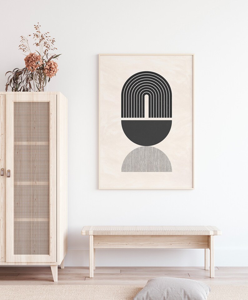 Pu&ograve; includere: Una stampa d'arte astratta geometrica in bianco e nero in una cornice di legno appesa a una parete bianca sopra una panca di legno. La stampa presenta un semicerchio nero, un arco nero con linee verticali e un semicerchio grigio.