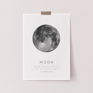 Op de afbeelding: Een zwart-witte print van de maan met de tekst "MOON" en een citaat van Neil Armstrong: "Here men from the planet Earth first set foot upon the Moon. We came in peace for all mankind. Neil Armstrong - July 1969."