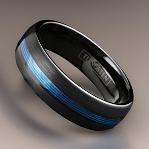Könnte beinhalten: Ein schwarzer Wolframring mit gebürsteter Oberfläche und drei blauen Linien um das Band. Das Wort "WOLFRAM" ist auf der Innenseite des Rings eingraviert.