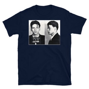 May include: A navy blue t-shirt with a black and white photo of two men in mugshots. The men are wearing suits and have their hair slicked back. The photo is labeled "Marion County Sheriff's Office" and "11 27 38 42799".