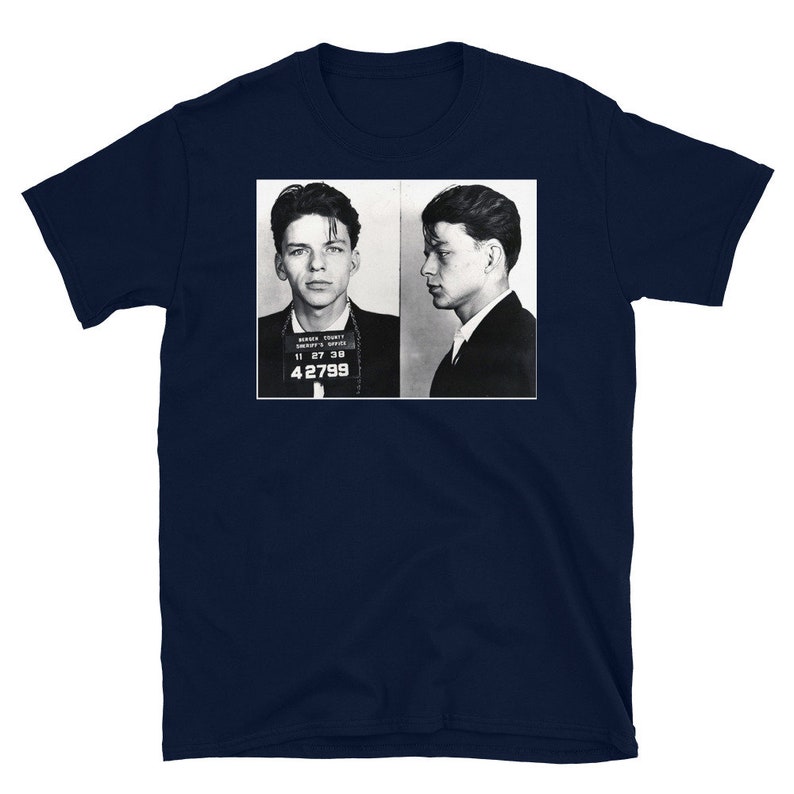 May include: A navy blue t-shirt with a black and white photo of two men in mugshots. The men are wearing suits and have their hair slicked back. The photo is labeled "Marion County Sheriff's Office" and "11 27 38 42799".