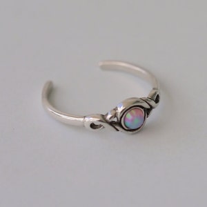 May include: A silver toe ring with a delicate design and a round iridescent opal gemstone.