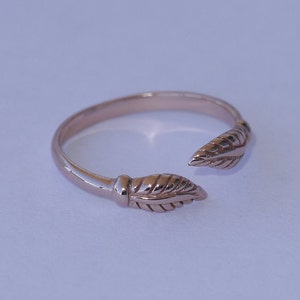 May include: A gold-toned ring with a leaf design on each side. The ring is open on one side, allowing it to be easily slipped on and off.