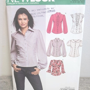 Peut inclure: Un patron de couture New Look avec une femme portant une chemise rayée. Le paquet comprend des illustrations de différents modèles de chemisiers, avec le texte "NEW LOOK" et des informations de taille.