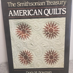 May include: A book cover for "The Smithsonian Treasury AMERICAN QUILTS" by Doris M. Bowman. The cover is black with white text and a quilt design. The quilt design has four starburst patterns in brown and cream colours.
