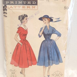 Peut inclure: Enveloppe de patron imprimé Butterick vintage avec des illustrations de deux robes boutonnées, une rouge et une bleue. L'enveloppe indique une taille de poitrine de 32 et une taille 14.