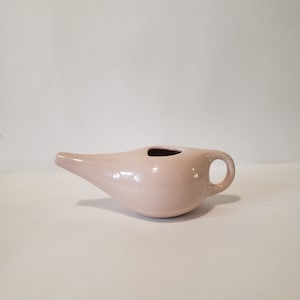 May include: A pale pink ceramic nasal douche with a spout and a handle.