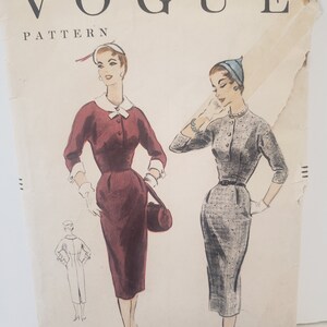Peut inclure: Un patron de couture Vogue vintage représentant deux femmes portant des robes. La femme de gauche porte une robe rouge avec un col blanc et des gants blancs. La femme de droite porte une robe grise avec un chapeau bleu. Le patron est pour la taille 14, avec un tour de poitrine de 81 cm et un tour de hanches de 89 cm. Le texte sur le patron indique "Vogue Pattern" et "Copyright 1955, The Conde Nast Publications Inc."