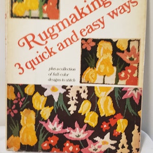 Peut inclure: Couverture de livre intitulée "Rugmaking: 3 quick and easy ways" par Joan Scobey & Marjorie Sablow. La couverture présente un motif floral coloré avec des fleurs jaunes, rouges, roses et vertes sur un fond noir.