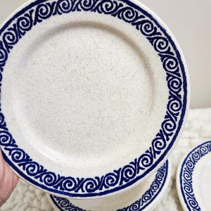 May include: Set of four white ceramic plates with a blue and white swirl design around the edge.