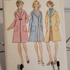 May include: A vintage Simplicity 6237 sewing pattern envelope featuring illustrations of three coats. The left coat is pink with a toggle closure, the centre is a blue and white houndstooth check, and the right is a tan coat over a blue turtleneck.
