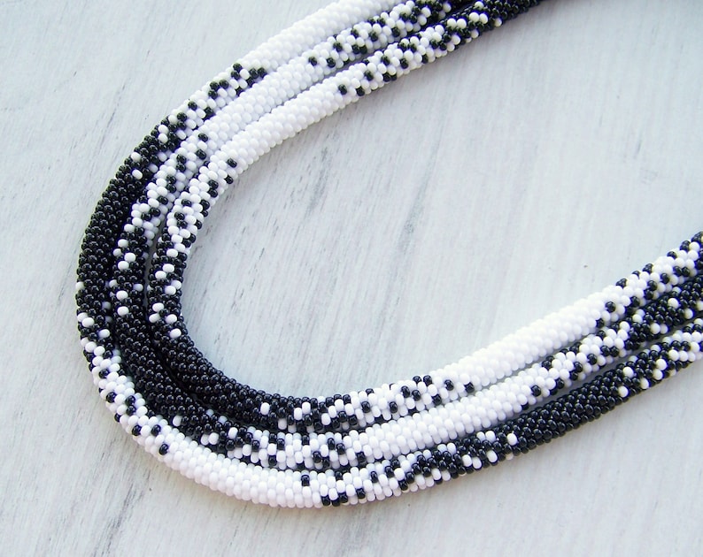 May include: A black and white beaded necklace with a graduated pattern. The necklace is made of small, round beads and is approximately 40 inches long.