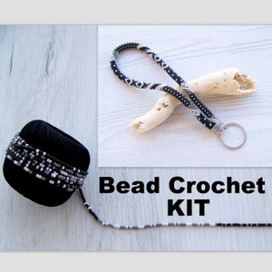 May include: A bead crochet kit with black, white, and gray beads. The kit includes a spool of beads, a finished beaded lanyard with a key ring, and a length of beaded cord.