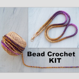 May include: A bead crochet kit with a gold and purple ombre beaded necklace, a spool of beads, and a small section of the beaded necklace.